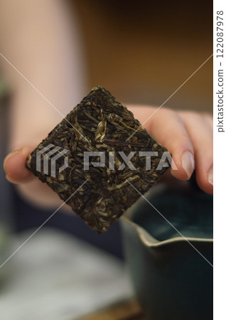 Hand holding a piece of pressed sheng pu erh tea. Chinese tea ceremony. 122087978