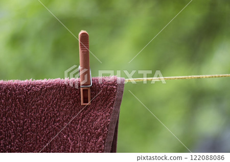 A pink towel with a pink clothespin is drying outside A pink towel with a pink clothespin is drying outside 122088086