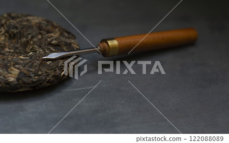 Pressed sheng puerh and a puerh knife on a black background 122088089