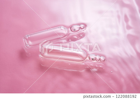 Ampoules in water on a pink background. 122088192