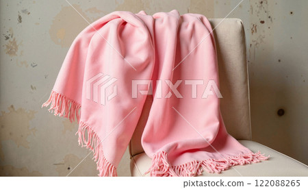 Cozy pink blanket draped elegantly over a chair against a textured wall backdrop 122088265