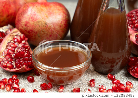 Pomegranate vinegar in a glass bowl among fresh pomegranate fruits. Pomegranate vinegar in a glass bowl among fresh pomegranate fruits. 122088492
