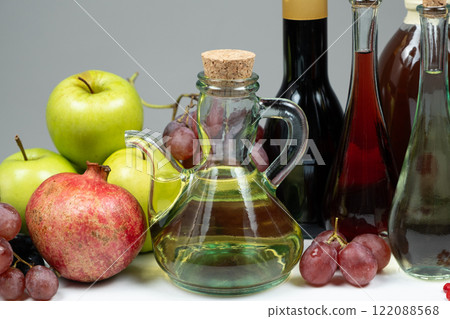 Different types of vinegar apple, wine and pomegranate in vinegar bowls among fruits. Different types of vinegar apple, wine and pomegranate in vinegar bowls among fruits. 122088568