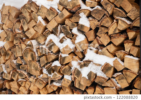 birch firewood. neatly stacked pile of firewood is partially covered in snow, a cold winter environment. warmth for cozy evenings in a rural setting 122088820