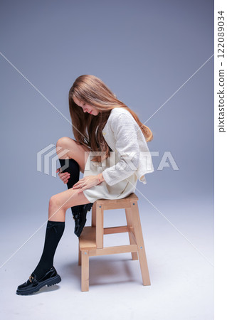 A Stylish Young Woman Sitting on a Stool with Long Hair, Exuding Beauty and Grace A Stylish Young Woman Sitting on a Stool with Long Hair, Exuding Beauty and Grace 122089034