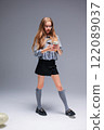 A Trendy Young Girl Dressed in Stylish and Chic Attire, Holding a Smartphone in a Creative Manner 122089037