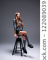 A Charming Fashion Model Posing Elegantly on a Stylish Stool Wearing a Trendy Outfit 122089039