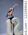 A Cheerful and Joyful Model Posing with a Colorful Inflatable Number 12 in a Studio Setting 122089042