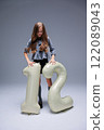 A young girl with an inflatable item sized 12 inches poses during a vibrant fashion photo shoot 122089043