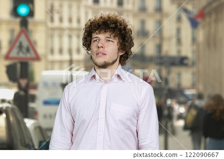 Portrait of a happy young attractive man with curly hair standing outdoors. City street in the background. Portrait of a happy young attractive man with curly hair standing outdoors. City street in the background. 122090667