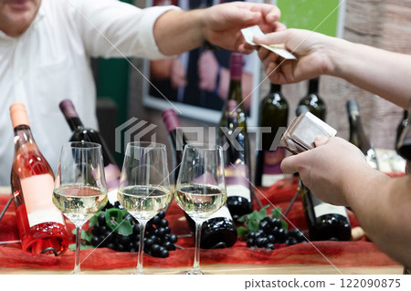 buyer's hand taking a bottle of wine from stand buyer's hand taking a bottle of wine from stand 122090875
