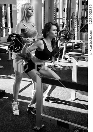Two beautiful girls working out in gym Two beautiful girls working out in gym 122090886