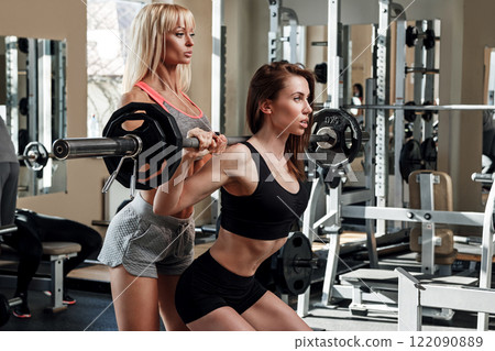 Two beautiful girls working out in gym 122090889