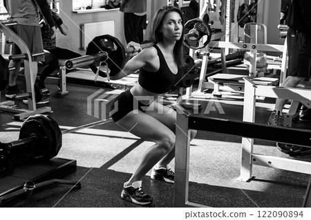 Beautiful woman with barbell on her shoulders 122090894
