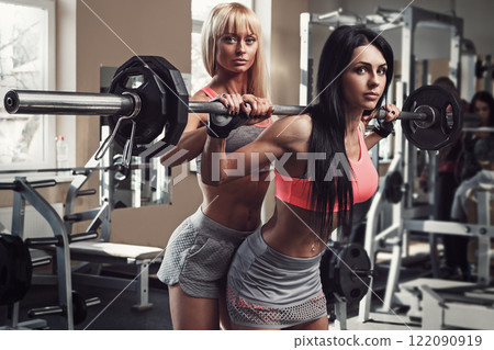 Two beautiful girls working out in gym 122090919