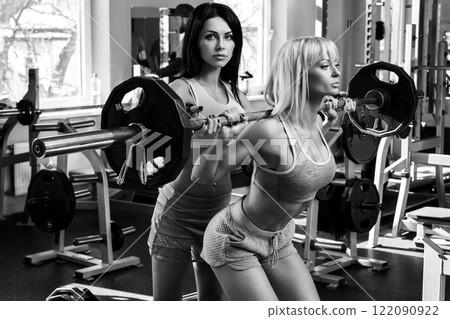 Two beautiful girls working out in gym Two beautiful girls working out in gym 122090922