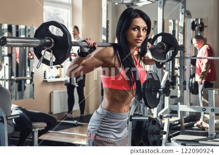 Brunette during workout with a barbell in gym Brunette during workout with a barbell in gym 122090924