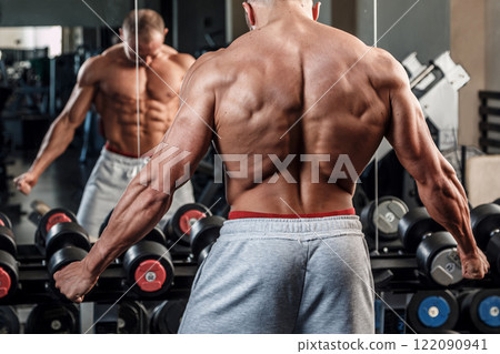 Young man showing his muscular back in gym Young man showing his muscular back in gym 122090941