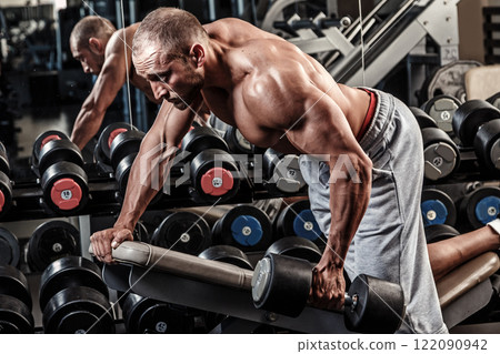 Young and muscular man working out with dumbbell Young and muscular man working out with dumbbell 122090942