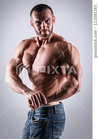Handsome muscular man wearing jeans posing in studio Handsome muscular man wearing jeans posing in studio 122091265