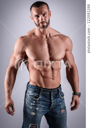 Handsome muscular man wearing jeans posing in studio Handsome muscular man wearing jeans posing in studio 122091266