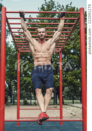 Muscular man doing pull-ups on horizontal bar 122091278