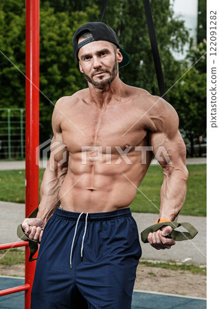 Man during workout with suspension straps on street Man during workout with suspension straps on street 122091282