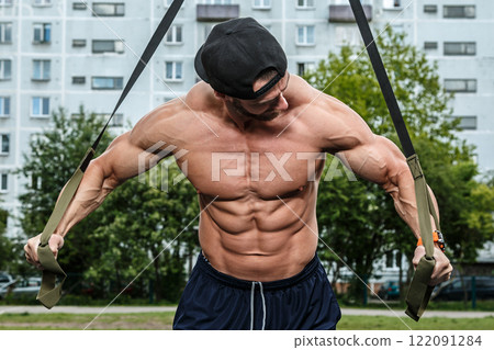 Man during workout with suspension straps on street Man during workout with suspension straps on street 122091284