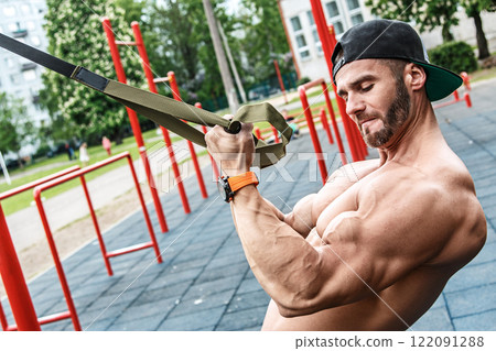 Man during workout with suspension straps on street 122091288