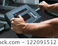 Male hands on control panel of cardio machine 122091512