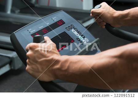 Male hands on control panel of cardio machine Male hands on control panel of cardio machine 122091512