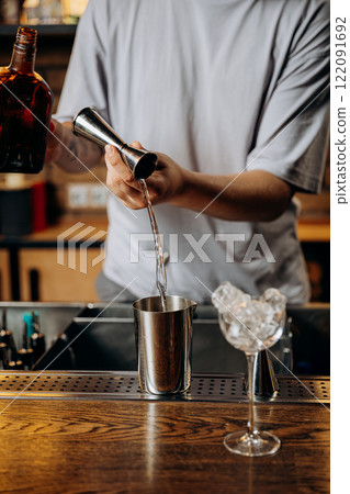 Bartender pouring liquor into a jigger, showcasing the precision of cocktail craftsmanship Bartender pouring liquor into a jigger, showcasing the precision of cocktail craftsmanship 122091692