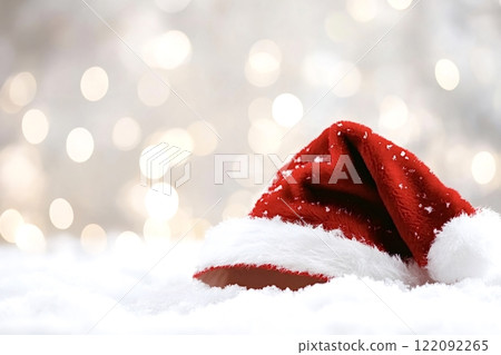 Santa claus hat lying on snow with sparkling christmas lights 122092265
