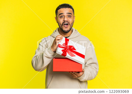 Man opening birthday gift box with red ribbon, receiving great present surprise, celebrating 122093069