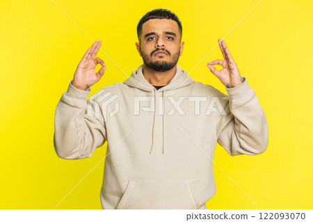 Indian man meditating breathes deeply with mudra yoga gesture, eyes closed, taking a break, relax Indian man meditating breathes deeply with mudra yoga gesture, eyes closed, taking a break, relax 122093070