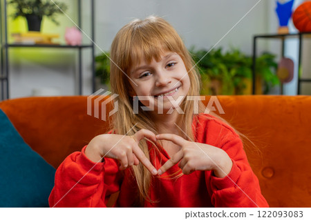 Young child kid girl makes symbol of love, showing heart sign to camera, express romantic feelings 122093083