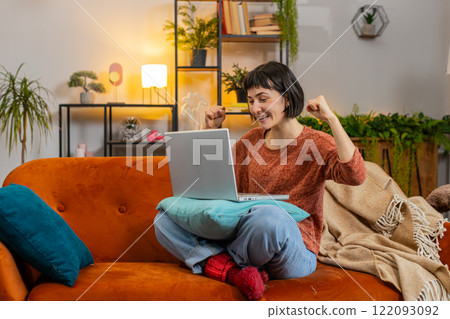Woman using laptop, receive good news shocked by sudden victory celebrate lottery jackpot win Woman using laptop, receive good news shocked by sudden victory celebrate lottery jackpot win 122093092