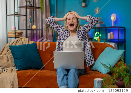 Happy woman using laptop receive good news shocked by victory celebrate lottery jackpot win at home Happy woman using laptop receive good news shocked by victory celebrate lottery jackpot win at home 122093139