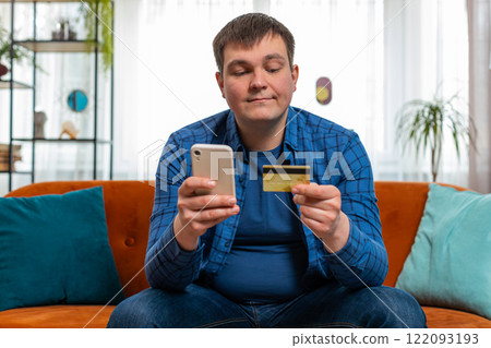 Man using credit bank card and smartphone while transferring money purchases online shopping home 122093193