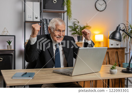 Senior happy Caucasian businessman working on laptop shocked by sudden victory at home office desk 122093301
