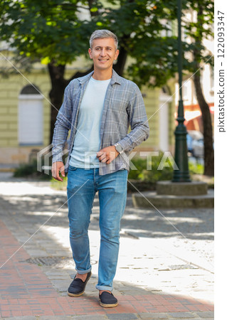 Smiling mature man in casual clothes walking in urban city street background in summer outdoors 122093347