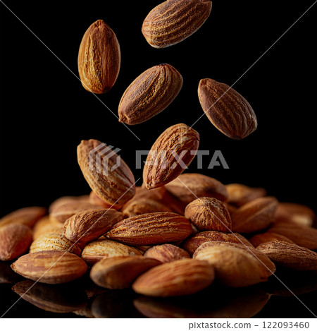 Photo of falling roasted almonds on a black background Photo of falling roasted almonds on a black background 122093460