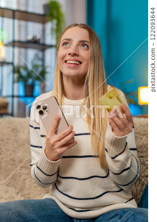 Caucasian woman paying purchase on sofa with mobile phone credit card smiling successful indoors 122093644