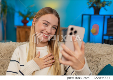 Caucasian woman smiling laughing talking during phone video call on sofa at home joyful emotions 122093645