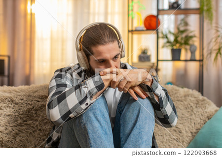 Man sad at home with headphones melancholic music track tearful mood quiet heartbreak divorce moment Man sad at home with headphones melancholic music track tearful mood quiet heartbreak divorce moment 122093668