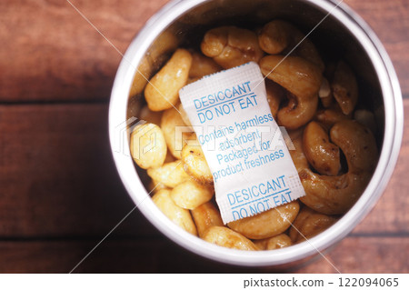 A container filled with cashew nuts accompanied by a desiccant pack A container filled with cashew nuts accompanied by a desiccant pack 122094065