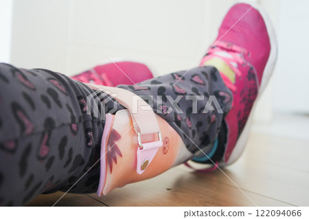 Close-Up of Child's Leg with Orthopedic Brace and Pink Sneakers 122094066