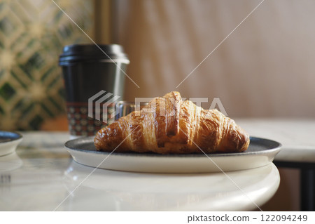 Enjoy a Delicious Fresh Croissant and Coffee Delightfully Presented on a Table Enjoy a Delicious Fresh Croissant and Coffee Delightfully Presented on a Table 122094249