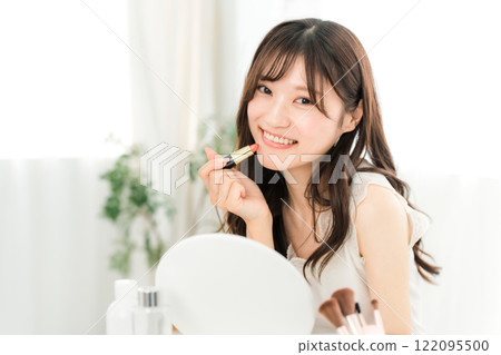 Young Asian woman applying make-up (lipstick, rouge, gloss, lips) 122095500