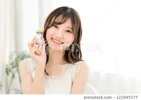 Smiling Asian woman holding a bottle of medicine/supplements Smiling Asian woman holding a bottle of medicine/supplements 122095577